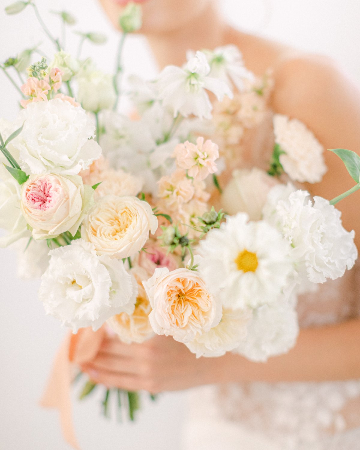 Bridal bouquet in peach and white tones, held by the bride